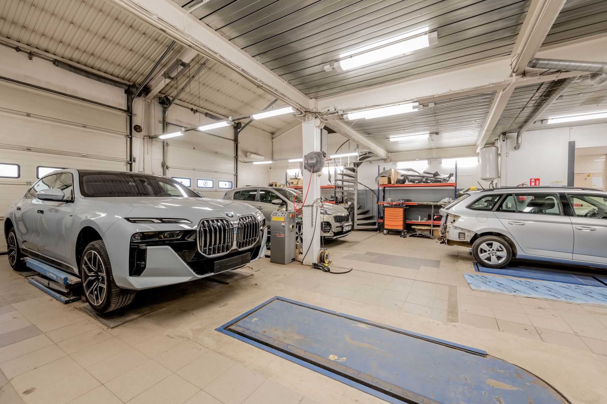 Cars positioned on service lifts inside a bright automotive repair workshop.